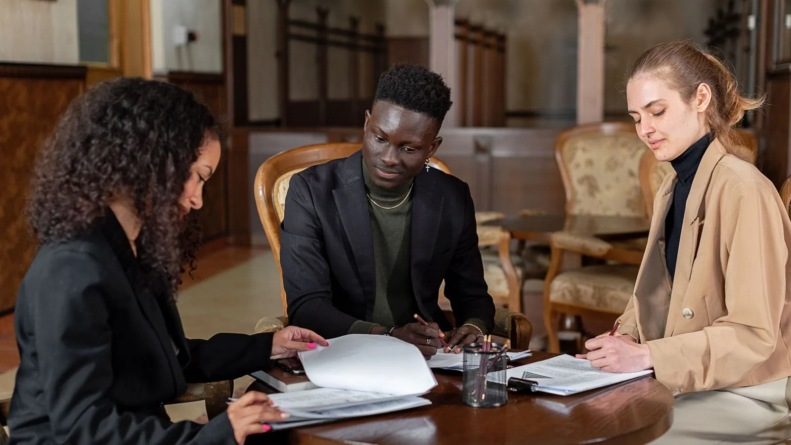 Three colleagues discussing printed paperwork