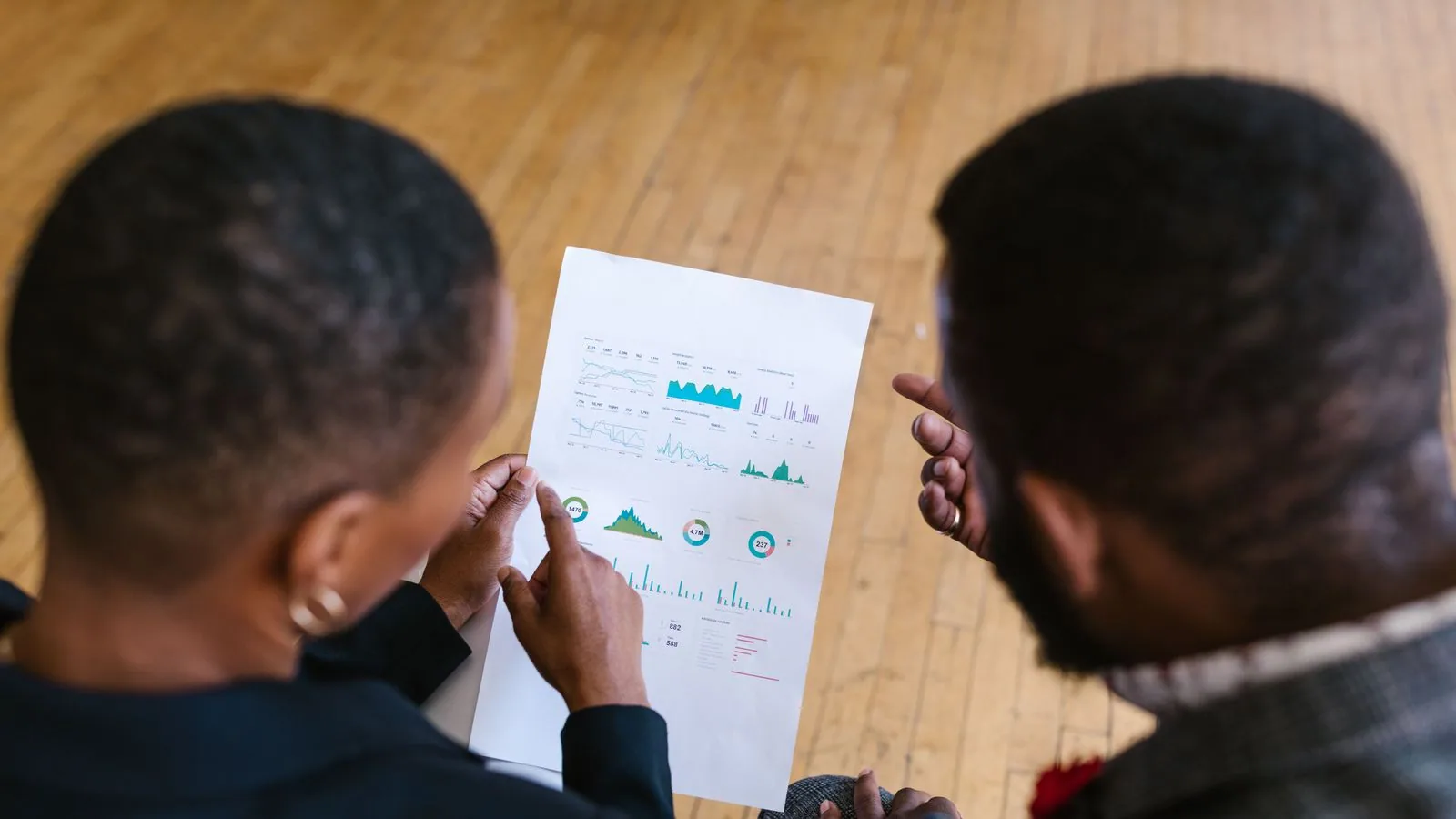 Two colleagues studying financial charts on paper
