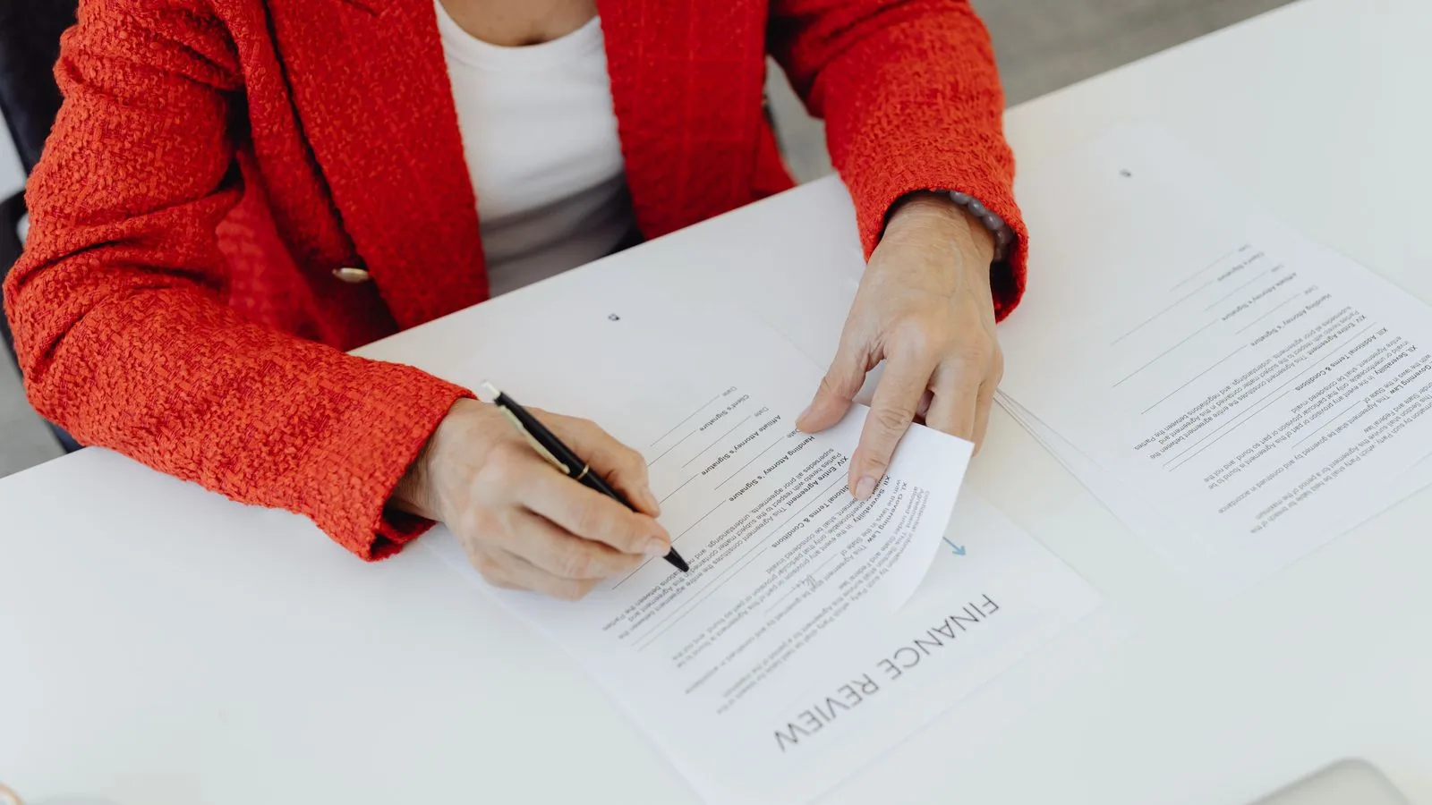 A person writing notes on a printed finance review