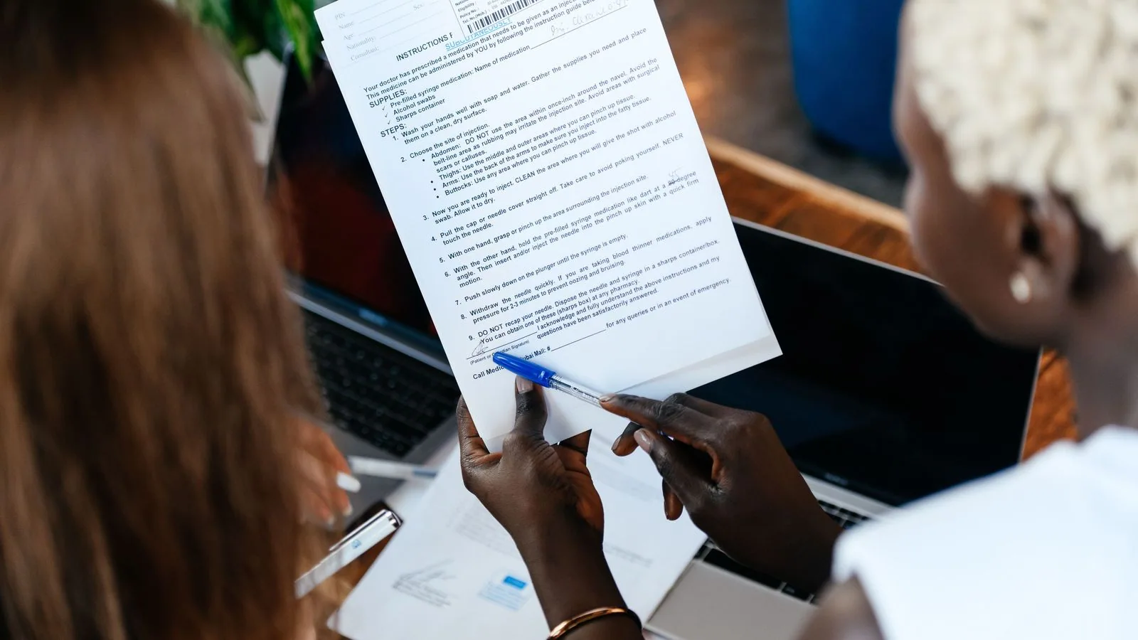 Colleagues comparing a printed document with a laptop