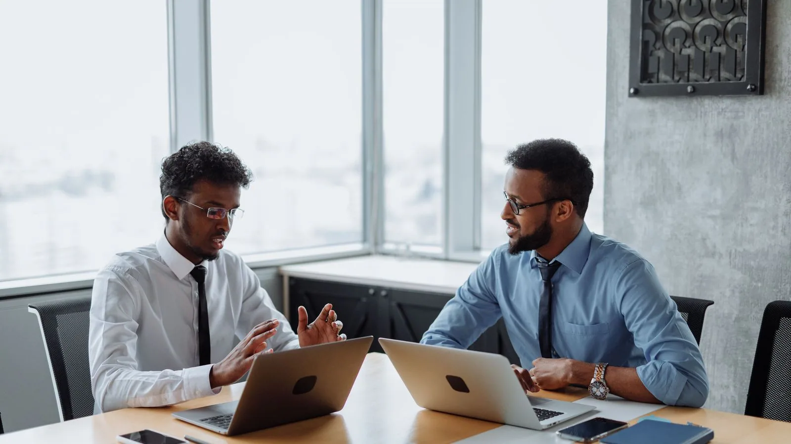 Two colleagues discussing information on their laptops